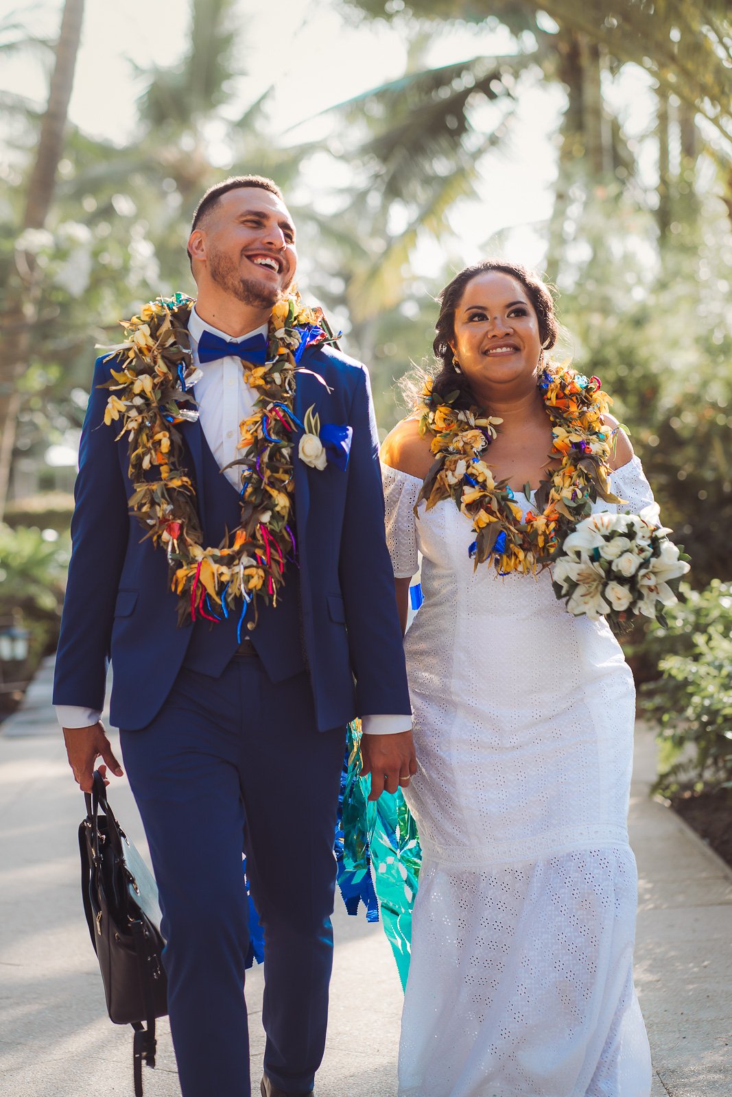 Anna et Alban marchent sous les palmiers, colliers de fleurs, mariage Pacifique — Timi M. Bourdet