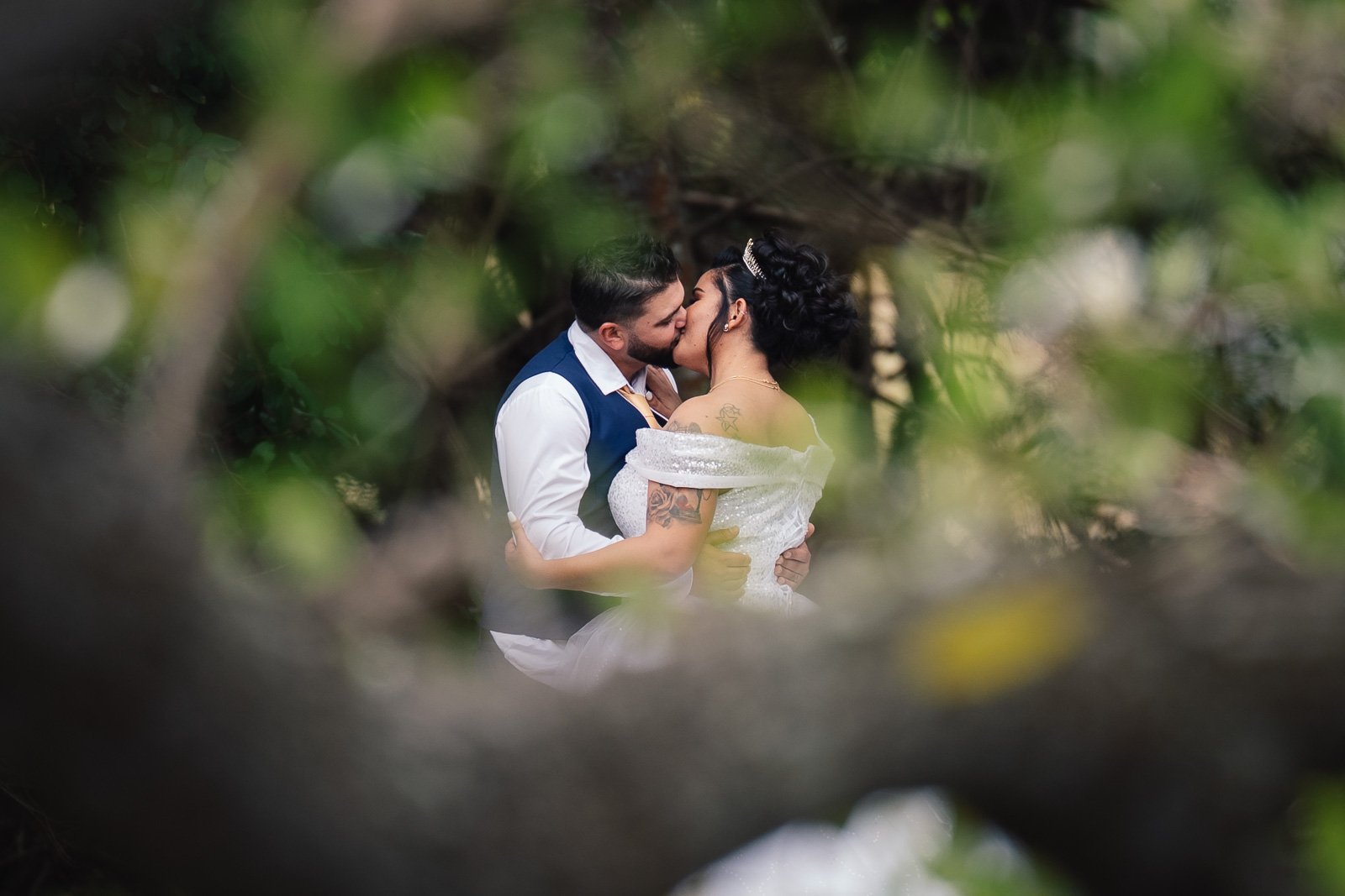 Baiser de Cydjie et Ryan à travers le feuillage, séance couple — Timi M. Bourdet