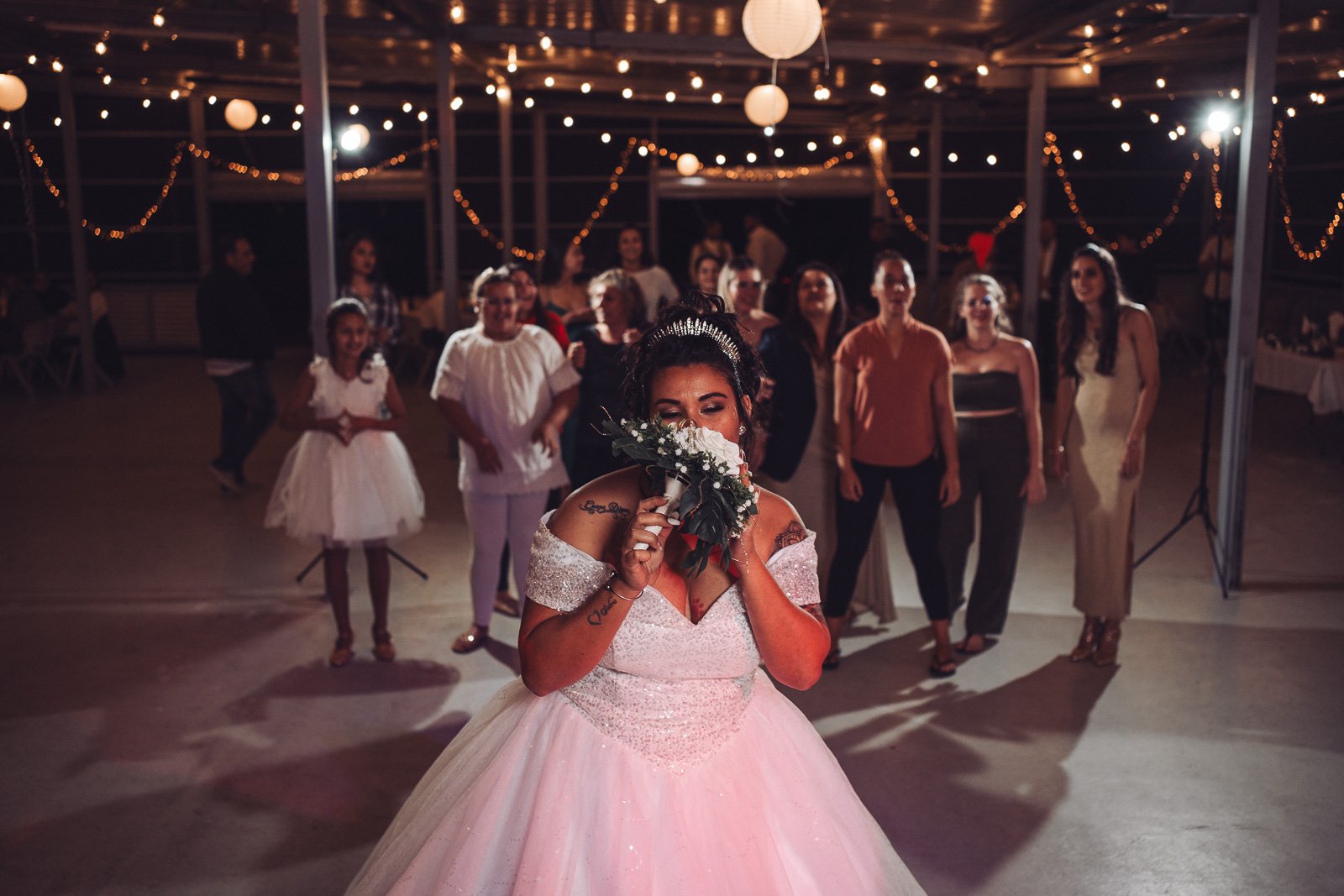 Cydjie prête à lancer son bouquet pendant la soirée, guirlandes lumineuses — Timi M. Bourdet