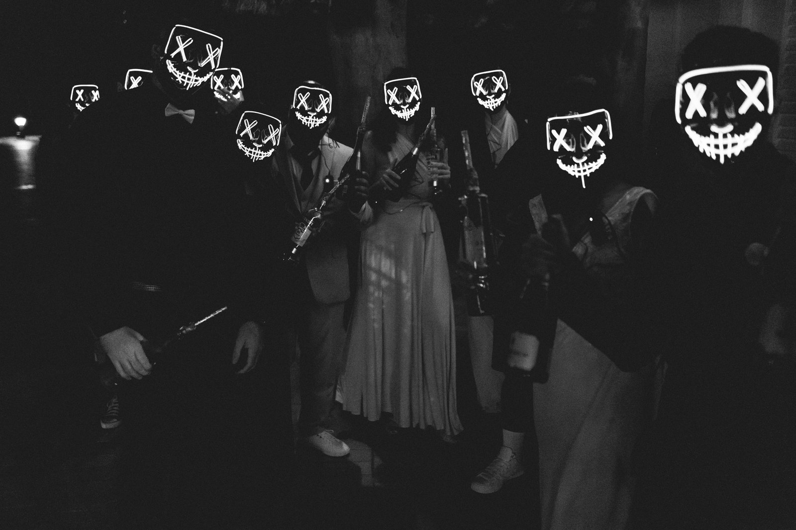 Soirée de mariage en noir et blanc, cortège masqué de néons lumineux dans la pénombre — Timi M. Bourdet