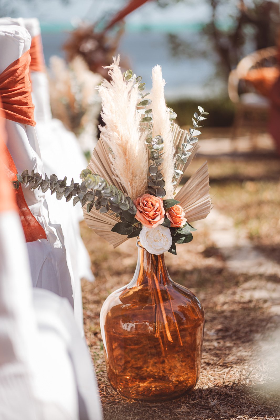Décor de cérémonie bohème face au lagon, pampas et roses pêche — Timi M. Bourdet